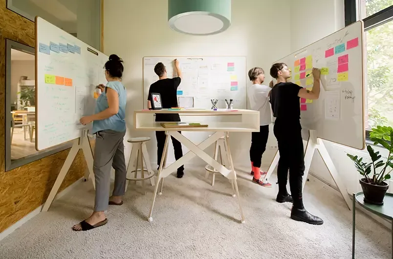 Team arbeitet gemeinsam an einer Wand voller Zettel
