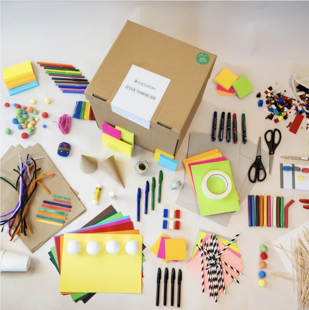 Innovatory Design Thinking Box mit ausgebreitetem Workshopmaterial